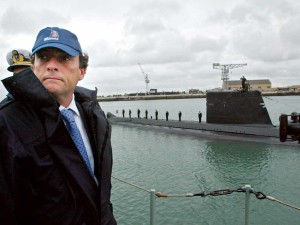 O Ministro da Defesa Nacional com um chapéu da marinha durante a viagem de lancha que o levou à Base Naval do Alfeite, para a cerimónia de assinatura. Ao fundo um submarino.